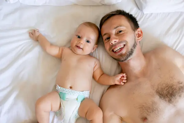 침대에 누워있는 아버지와 귀여운 신생아의 초상화 상단보기 — 스톡 사진
