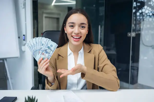 Cheerful young woman showing on video call dollars cash won in lottery or casino. Concept of lending, success and winning. Successful female happy show the income