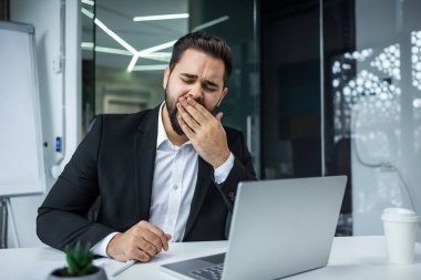 Sıkılmış esneyen beyaz erkek, beyaz iş adamı tembel ofis çalışanı yönetici içeride bilgisayarla çalışıyor. Uykuya ihtiyacı var.