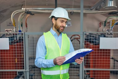 caucasian man contractor, engineering holding clipboard, wear jacket and inspect plant heating room