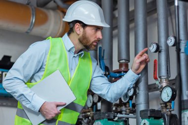 Genç mühendis fabrika kontrol odasında, notlar alarak portresi