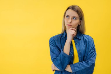 Çekici şüpheli kadın parlak sarı arka planda izole edilmiş yeni plan kopyalama alanı yaratmayı düşünüyor.