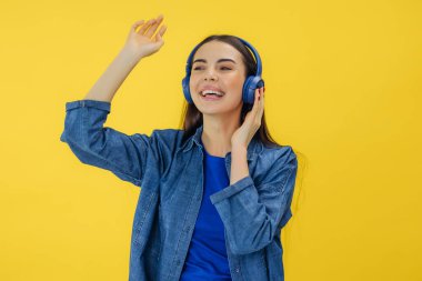 Kaygısız Kafkasyalı esmer kadın boş zamanlarında eğleniyor müzik dinliyor ve sarı arka planda dans ediyor..