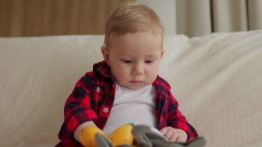 Bebek çocuk evdeki kanepede oyuncak kullanıyor. Dünyayı, renkleri, şekilleri öğreniyor.