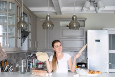 Bir kadın yeni sarılmış hamuru gösteriyor. Kadın mutfakta yemek hazırlıyor.