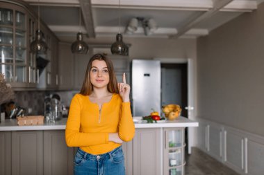 Yeni bir fikir. Neşeli genç bir kadın işaret parmağını kaldırıyor.