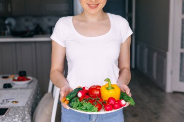 Bir tabak taze sebzeli ince kadın..