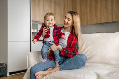 Oturma odasında oynayan tatlı bir kadın ve çocuk. Anne ve oğlu güler Mutlu aile. Genç anne ve oğlu evde birlikte aktiviteler yapıyorlar..