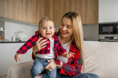 Güzel anne ve oğul evdeki kanepede otururken kameraya bakıp gülümsüyor.