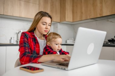 Çalışan anne, dizüstü bilgisayar ve evde bebekle uzaktan çalışma süresi için yazı. Anne, çocuk ve hayat dengesi dizüstü bilgisayarla, verimlilikle ve iş sahibiyle