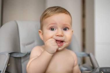 Pis pasaklı çocuk beslenme sandalyesinde yemek yiyor.