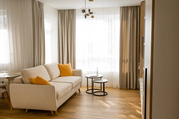Modern interior with design comfortable sofa, furniture, coffee tables, pillows in stylish home decor. Neutral living room.
