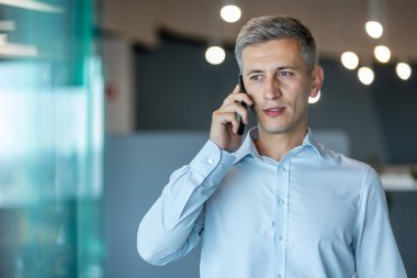 Açık mavi gömlekli profesyonel bir işadamı bir telefon görüşmesi yapıyor..