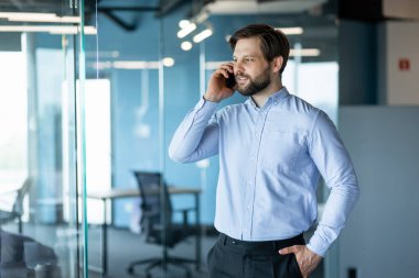 Kendine güveni tam bir iş adamı. Parlak, modern bir ofis alanında telefon görüşmesi yapıyor..