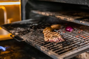 Lezzetli bir biftek ve ızgarada mangal yapan çeşitli sebzeler. Sahne, sıcak ve cızırtılı bir atmosferle kırsal yemekleri yakalıyor, aşçılık becerilerini ve lezzetli yemek hazırlıklarını vurguluyor..