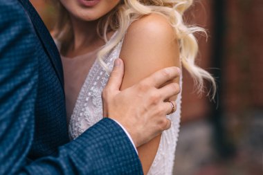 Gelin ve damat şehrin ıssız caddelerinde yürüyor. Yeni evliler yakınlarda duruyor ve güzel bir evin turuncu duvarının yanında sarılıyorlar..