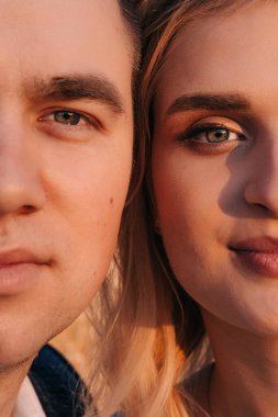 Yeni evlilerin yüzlerinin bir kısmının yakın plan portresi. Düğün günlerinde mutlu bir çiftin portresi, güzel giyimli yeni evliler parkta yürürken şefkatle kucaklaşırlar..