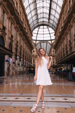 Galleria Vittorio Emanuele II 'nin dışındaki beyaz elbiseli kadın portresi. Milan moda tarzı. Kameraya bak..