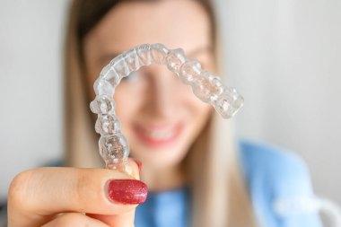 Kadınların el ele tutuşması geçersiz, şeffaf hizalama, görünmez diş teli ya da arka planda bulanık mil ile ortodontik silikon çalıştırıcı. Güzel bir gülümsemeye sahip olmanın yolu.