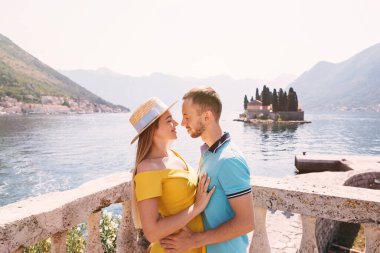 Genç bir çift, sıcak güneşin altında güzel bir gölün kenarında romantik bir anın tadını çıkarıyor. Göz kamaştırıcı dağlar ve sakin suyla çevrili güzel bir yaz kaçamağında neşeli bir bağı paylaşıyorlar..