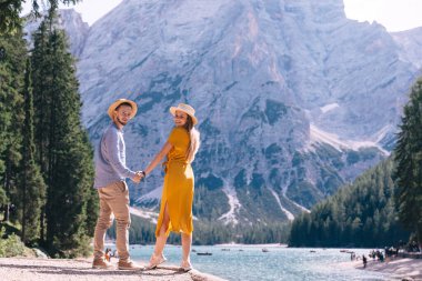 İtalya 'daki kayalık dağlar ve göl manzarasında el ele tutuşan çift, Dolomitler.