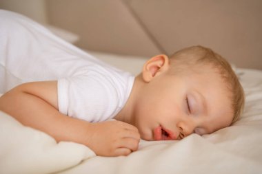 Rahat beyaz bir yatakta huzur içinde uyuyan bir çocuğun huzurlu bir görüntüsü..