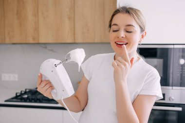 Modern bir mutfakta bir kadın gülümser ve elini karıştırır. Yemek pişirme, ev yemeği pişirme ve aşçılık hevesi..