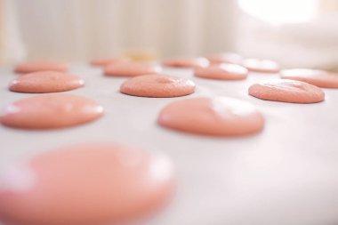 Pembe makarna hamuru mermileri fırına düzgünce yerleştirilmiş.