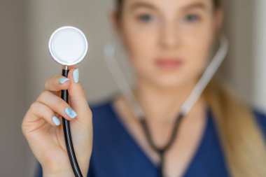 Steteskop tutan, sağlık ve bakımı vurgulayan tıbbi bir kişinin odaklanmış görüntüsü.