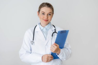 Profesyonel kadın doktor, steteskop takarken, klinik ya da sağlıkla ilgili bir ortamda güven ve uzmanlık aktarırken, kendine güvenen bir pano ile poz veriyor..