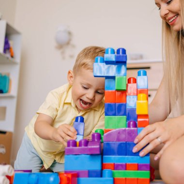 Genç bir çocuk ve yetişkin renkli oyuncak bloklarını eğlenceli bir ev ortamında, eğlenceli ve eğitici aktivitelerde bir araya getirmekten zevk alırlar..