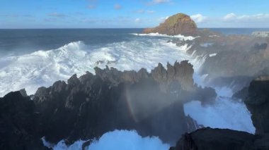 Porto Moniz, Madeira, Portekiz 'de Atlantik kıyısında güçlü fırtına dalgaları ve gökkuşağı oluşumu