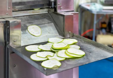Dilimlenmiş salatalık dilimlerini yiyecek endüstrisi için otomatik ticari sebze dilimleme makinesi tarafından doğrama işleminden sonra destek tabağına koy