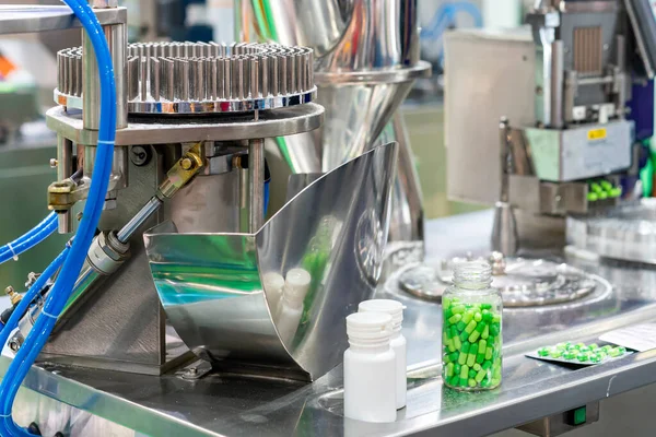 Yeşil kapsülü, tıbbi endüstriyel kapsül doldurma makinesinde şeffaf ve beyaz plastik şişelerle kapatın.