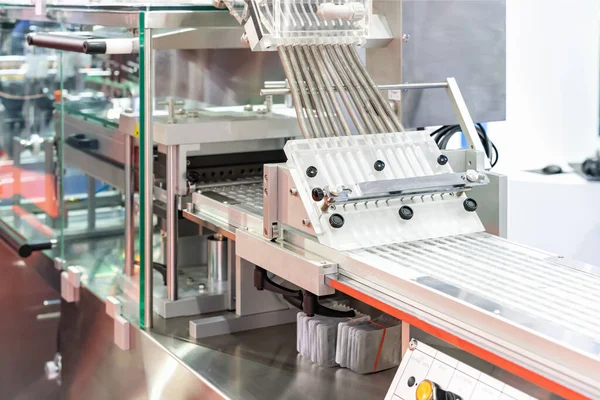 close up tablet or capsule feeding chute flow down to blister packaging of automatic continuous blister packing machine in pharmaceutical industrial