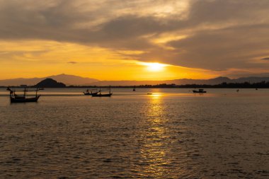 Siluet görüntü manzara akşam silueti okyanus üzerinde gün batımı balıkçı tekneleri ve arka planda dağ
