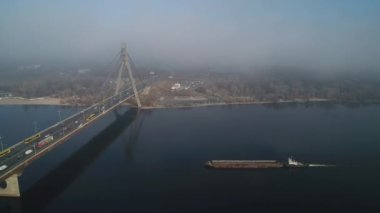 Cargo barge floats on the river, morning haze, fog over the water. Cinematic drone footage. Kyiv. Ukraine. Dnipro river.