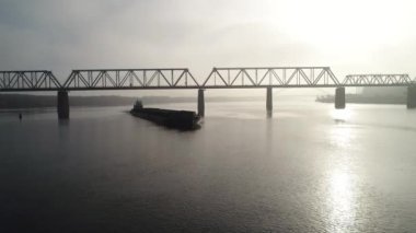 Cargo barge floats on the river, morning haze, fog over the water. Cinematic drone footage. Kyiv. Ukraine. Dnipro river.