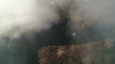 A fishing boat spits along the Desna river in the fog. Aerial. Ukraine. Kyiv. 