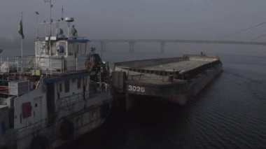 Cargo barge floats on the river, morning haze, fog over the water. Cinematic drone footage. Kyiv. Ukraine. Dnipro river.