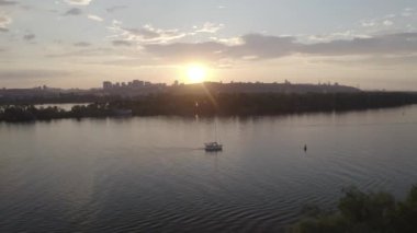The yacht sails along the Dnieper river at sunset. View of the general plan of the city. Silhouette of the city. Ukraine. Aerial. 
