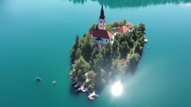 Gölün ortasındaki Mary Varsayımı Kilisesi Bled. Slovenya. Havadan. Yaz. İnsansız hava aracı videosu. Bled Gölü 'nde küçük bir adada uçmak. Mavi su ve orman..