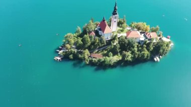 Gölün ortasındaki Mary Varsayımı Kilisesi Bled. Slovenya. Havadan. Yaz. İnsansız hava aracı videosu. Bled Gölü 'nde küçük bir adada uçmak. Mavi su ve orman..