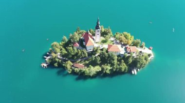 Gölün ortasındaki Mary Varsayımı Kilisesi Bled. Slovenya. Havadan. Yaz. İnsansız hava aracı videosu. Bled Gölü 'nde küçük bir adada uçmak. Mavi su ve orman..