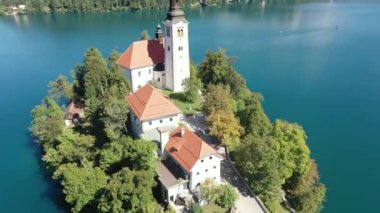 Gölün ortasındaki Mary Varsayımı Kilisesi Bled. Slovenya. Havadan. Yaz. İnsansız hava aracı videosu. Bled Gölü 'nde küçük bir adada uçmak. Mavi su ve orman..