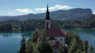 Gölün ortasındaki Mary Varsayımı Kilisesi Bled. Slovenya. Havadan. Yaz. İnsansız hava aracı videosu. Bled Gölü 'nde küçük bir adada uçmak. Mavi su ve orman..
