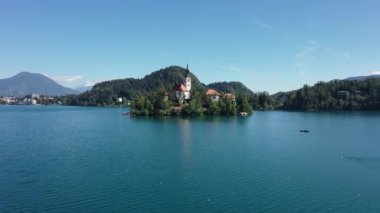 Gölün ortasındaki Mary Varsayımı Kilisesi Bled. Slovenya. Havadan. Yaz. İnsansız hava aracı videosu. Bled Gölü 'nde küçük bir adada uçmak. Mavi su ve orman..