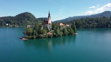Gölün ortasındaki Mary Varsayımı Kilisesi Bled. Slovenya. Havadan. Yaz. İnsansız hava aracı videosu. Bled Gölü 'nde küçük bir adada uçmak. Mavi su ve orman..
