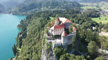 Slovenya 'daki Aerial of Bled Castle veya Blejski mezunu, ön planda Bled Gölü ve Karawanks Dağları ile birlikte. Yaz. İnsansız hava aracı videosu. Günaydın.