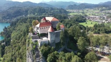 Slovenya 'daki Aerial of Bled Castle veya Blejski mezunu, ön planda Bled Gölü ve Karawanks Dağları ile birlikte. Yaz. İnsansız hava aracı videosu. Günaydın.